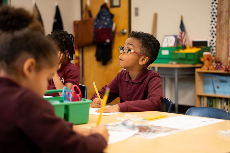 Kindergarten students working at a table with crayons and workbooks