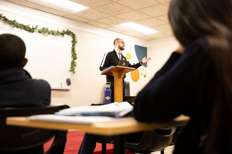 A teacher speaks to his class from a lectern
