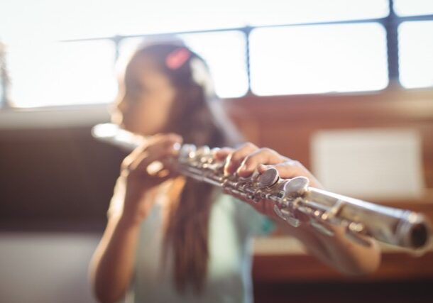 A girl practicing the flute in a classroom