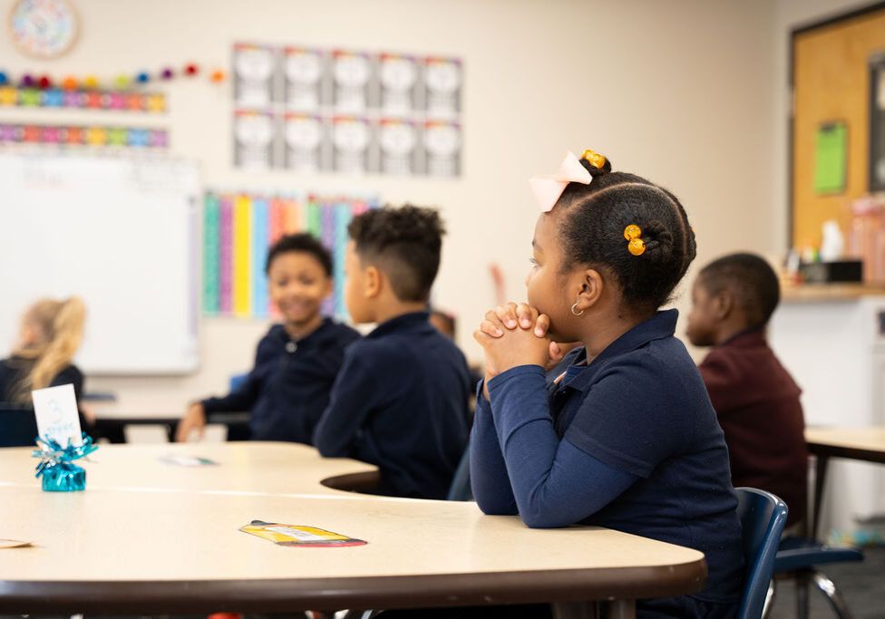Preschoolers at a table listening to their teacher