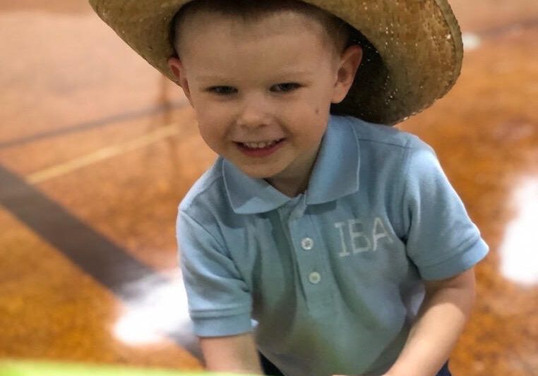 A smiling preschool boy in a cowboy hat