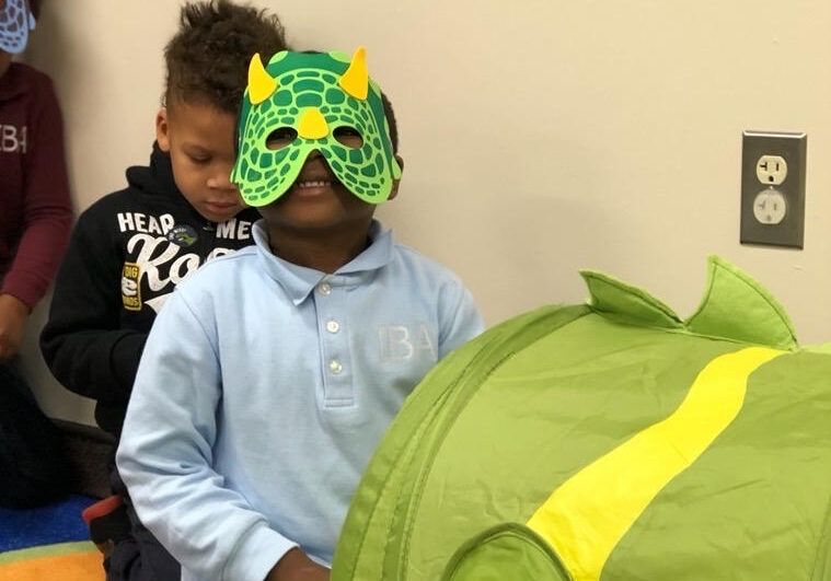 Preschoolers playing dress-up with a dinosaur mask